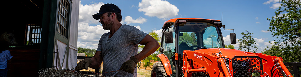 Man hauling hay next to a Kubota tractor